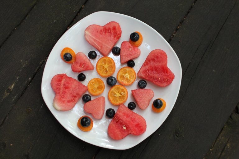 Can depression make you lose weight? Yes. Eating small, nutrient-dense meals can help. Oranges, blueberries, and watermelon cut into heart shapes are arranged on a white plate on a table.